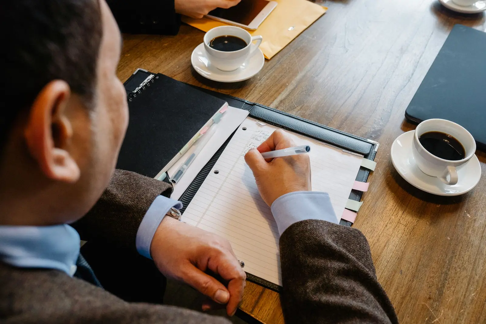 Writing a plan in a notebook beside a coffee