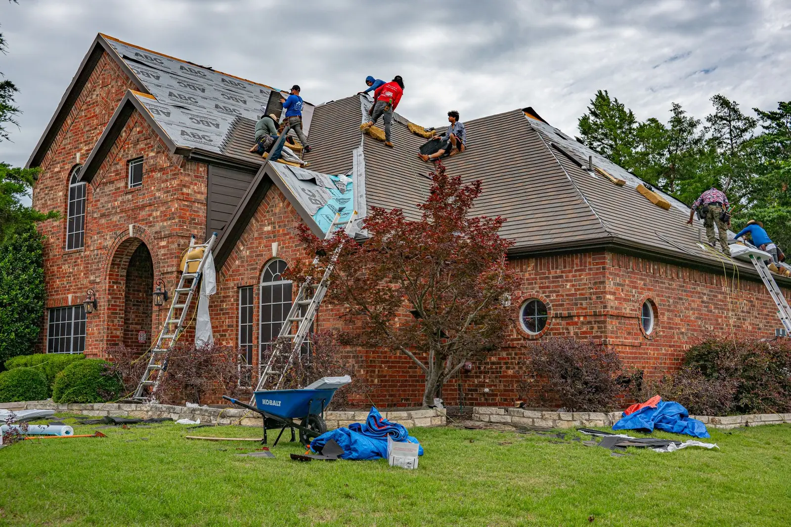 Roofers replacing the roof on a brick house