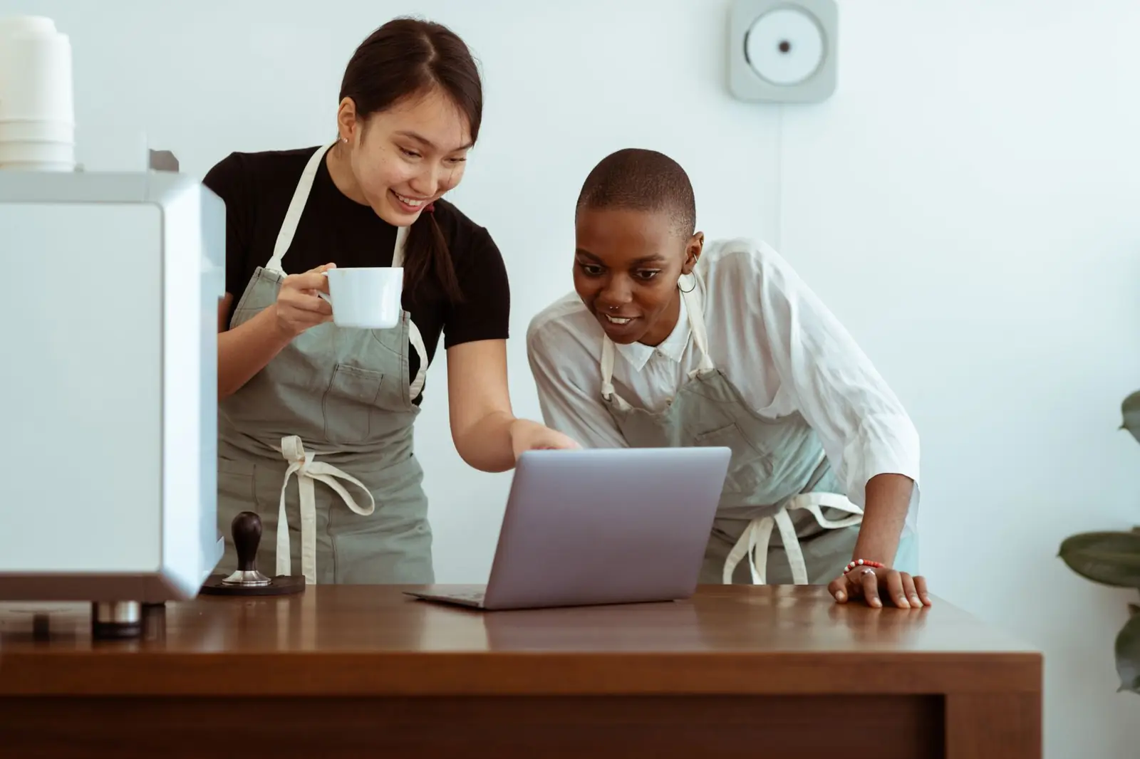 Two cafe owners looking at their laptop together